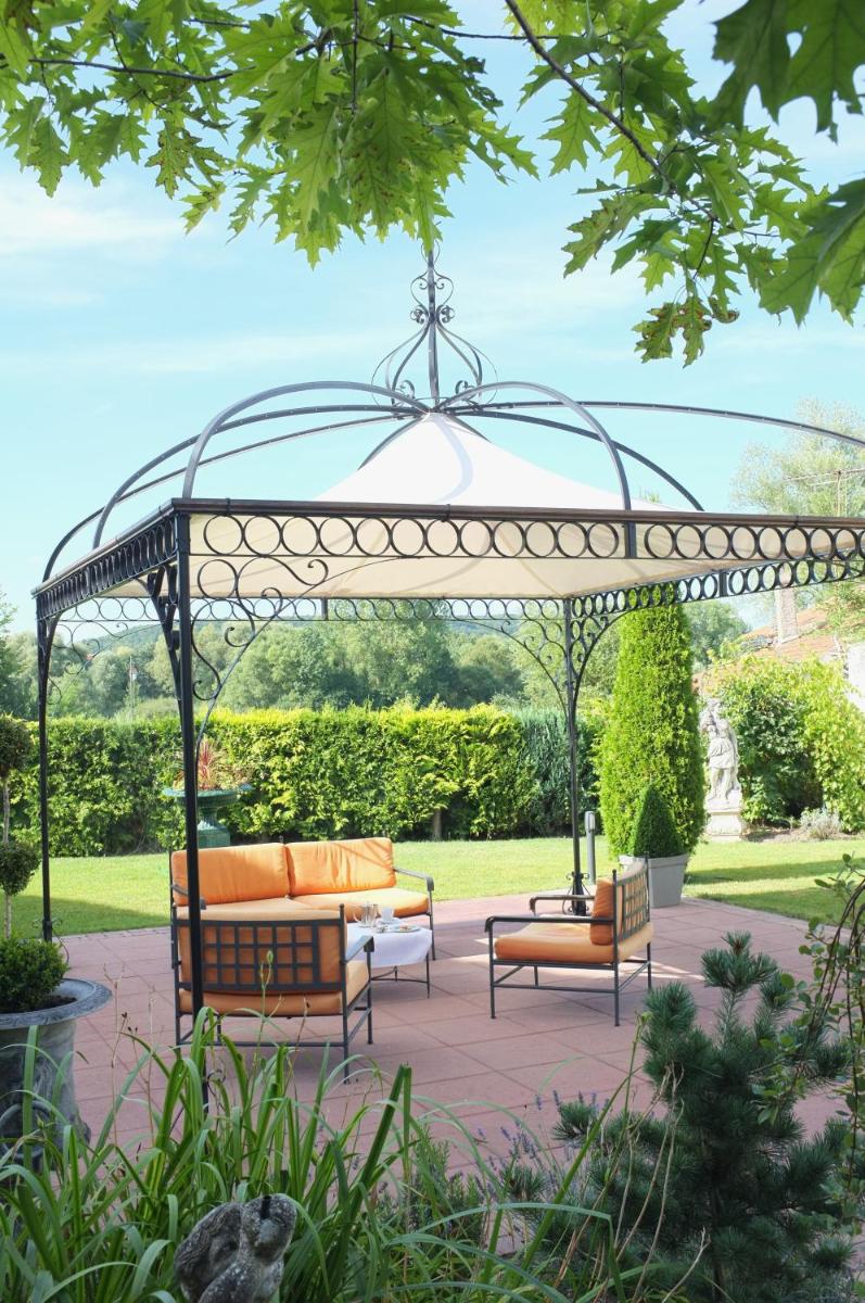 une pergola avec des canapés sur une terrasse dans l'établissement Hôtel du Domaine de La Grange de Condé, à Condé-Northen