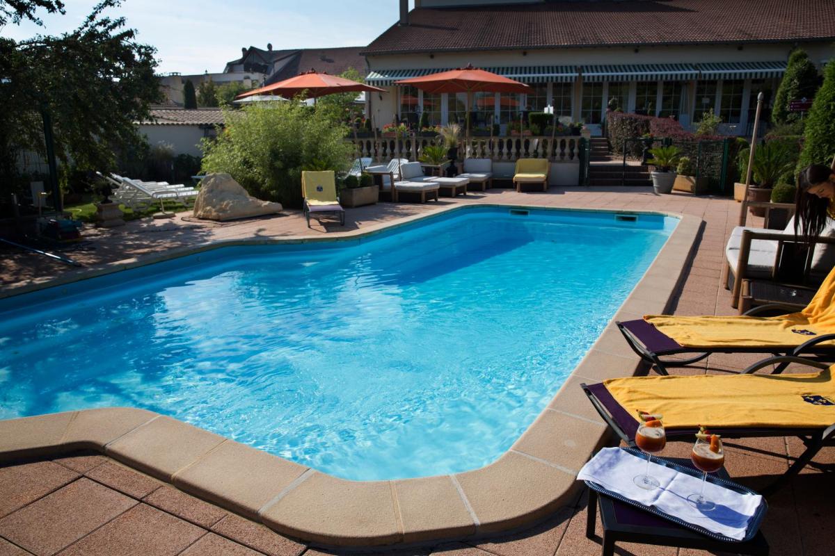 une grande piscine avec deux chaises et une table dans l'établissement Hôtel du Domaine de La Grange de Condé, à Condé-Northen 57 autres photos