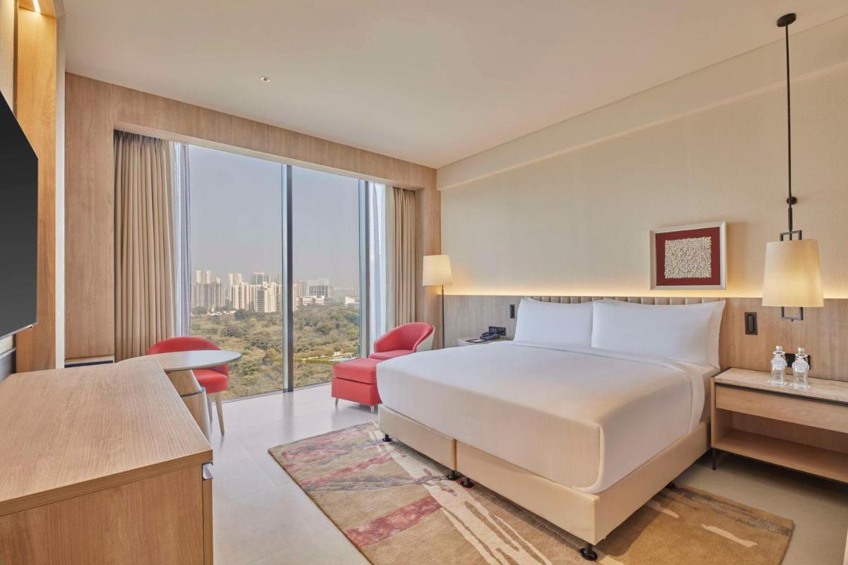 a hotel room with a bed and a large window at Hilton Gurugram Baani City Centre in Gurgaon