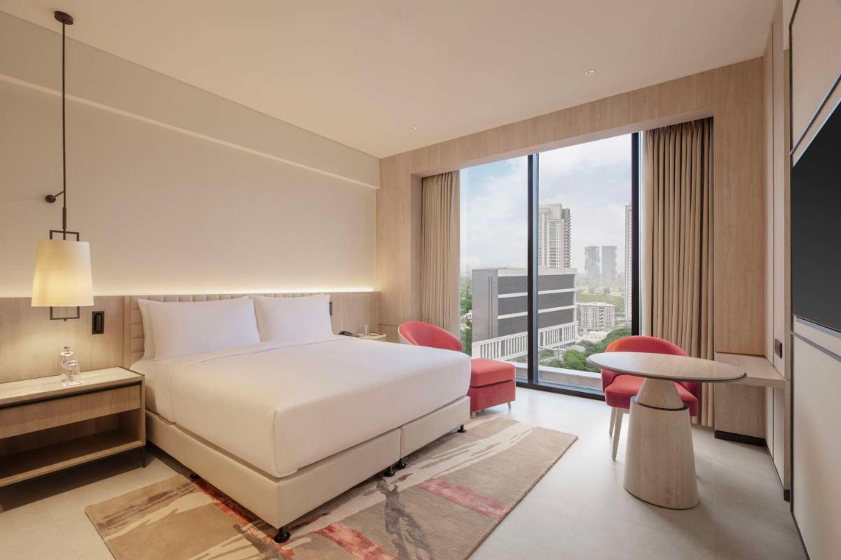 a hotel room with a bed and a large window at Hilton Gurugram Baani City Centre in Gurgaon