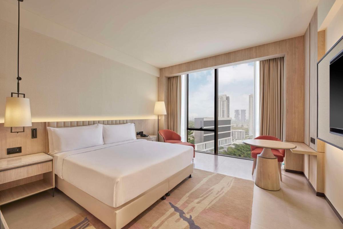 a bedroom with a white bed and a large window at Hilton Gurugram Baani City Centre in Gurgaon