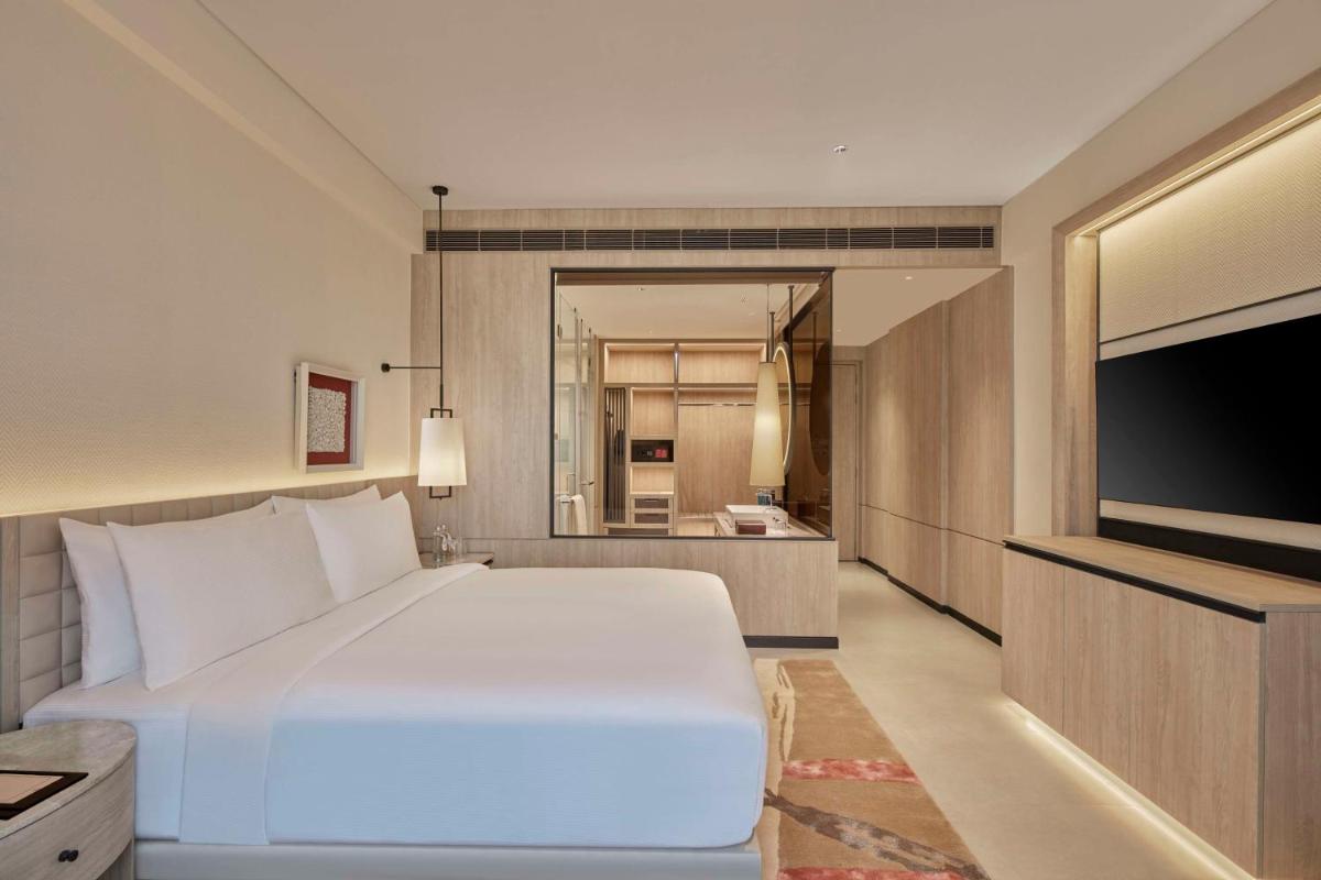 a bedroom with a large white bed and a television at Hilton Gurugram Baani City Centre in Gurgaon