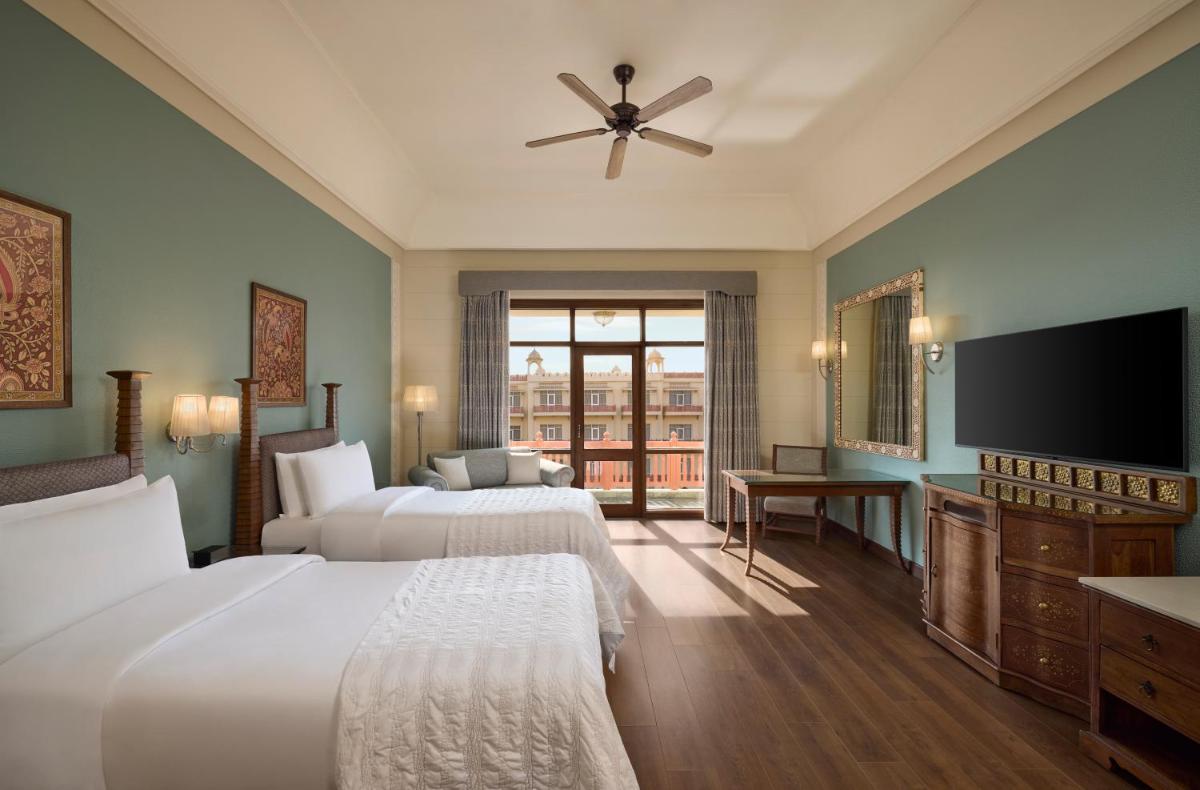 a hotel room with two beds and a flat screen tv at Le Meridien Jaipur Resort & Spa in Jaipur