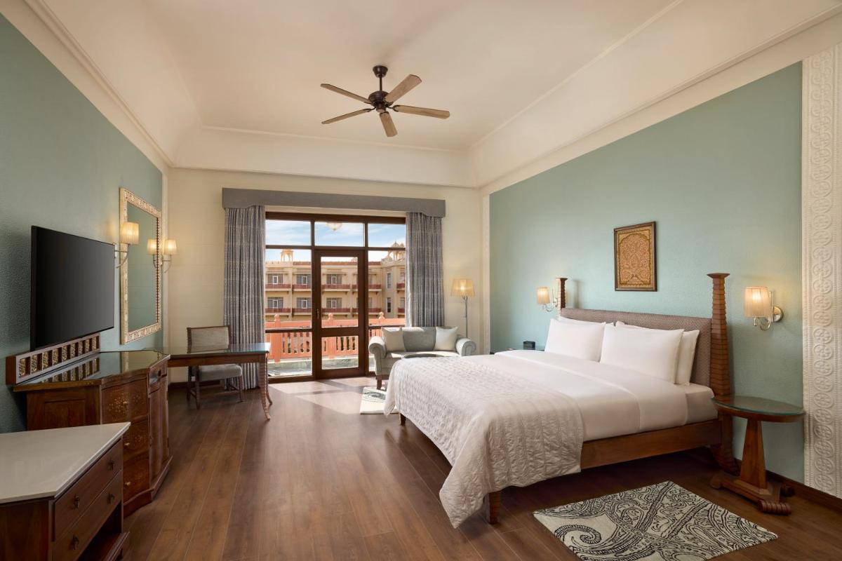 a bedroom with a bed and a large window at Le Meridien Jaipur Resort & Spa in Jaipur