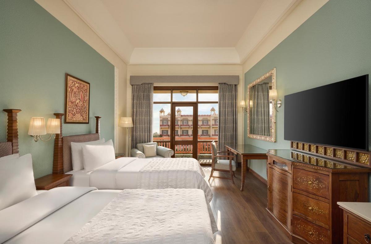 a hotel room with two beds and a flat screen tv at Le Meridien Jaipur Resort & Spa in Jaipur