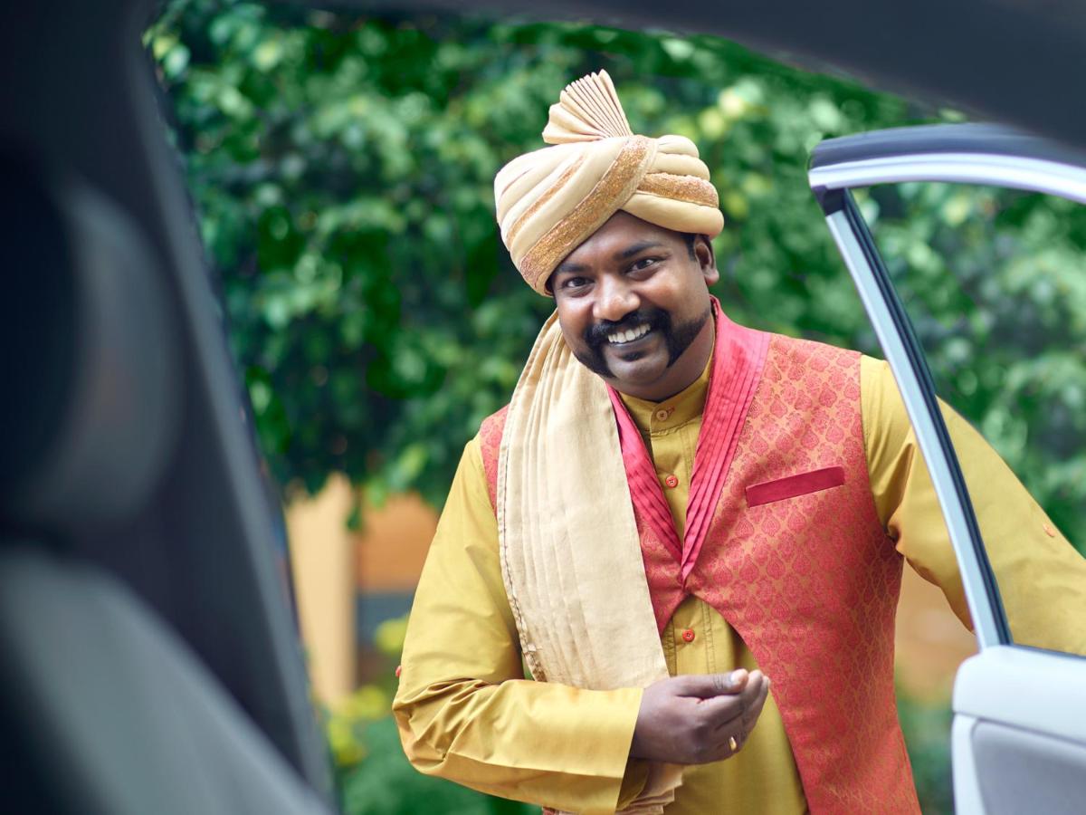a man wearing a hat standing next to a car at Shangri-La Bengaluru in Bengaluru a man wearing a hat standing next to a car at Shangri-La Bengaluru in Bengaluru