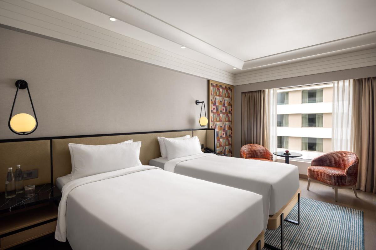 a hotel room with two beds and a window at Pullman Chennai Anna Salai - Premium Brand By Accor in Chennai