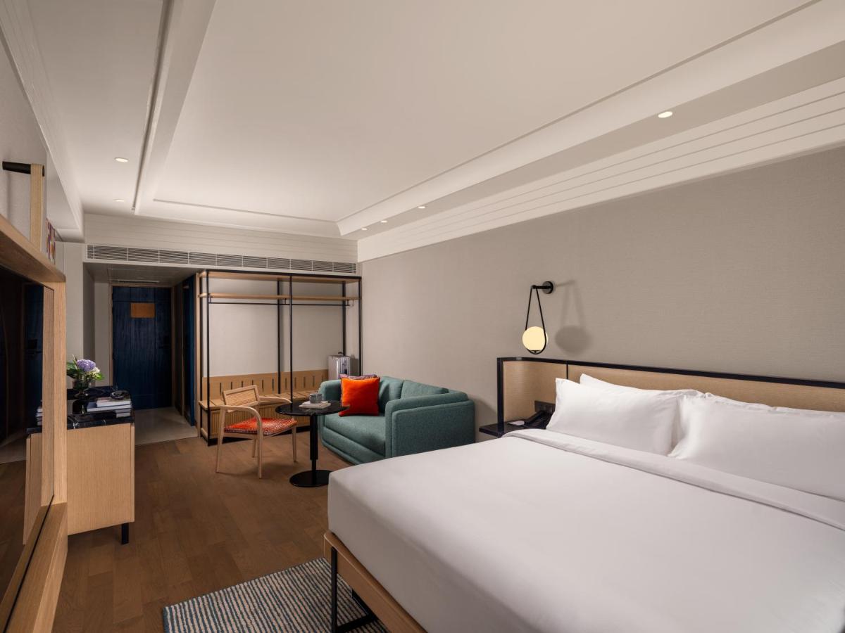 a hotel room with a bed and a chair at Pullman Chennai Anna Salai - Premium Brand By Accor in Chennai