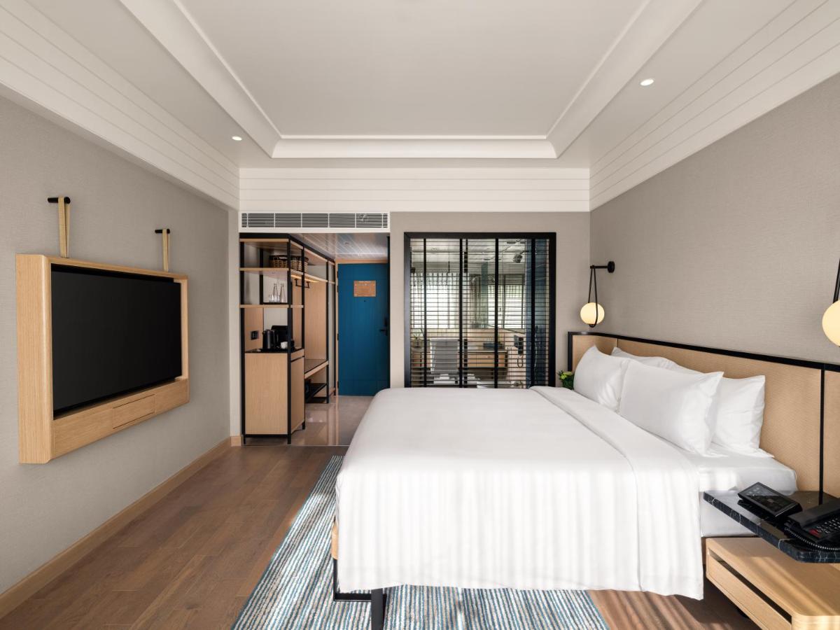 a bedroom with a large bed and a flat screen tv at Pullman Chennai Anna Salai - Premium Brand By Accor in Chennai