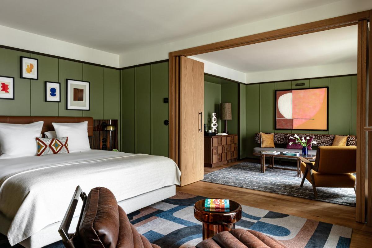 une chambre avec des murs verts, un lit et un canapé dans l'établissement Norman Paris Hôtel & Spa, à Paris