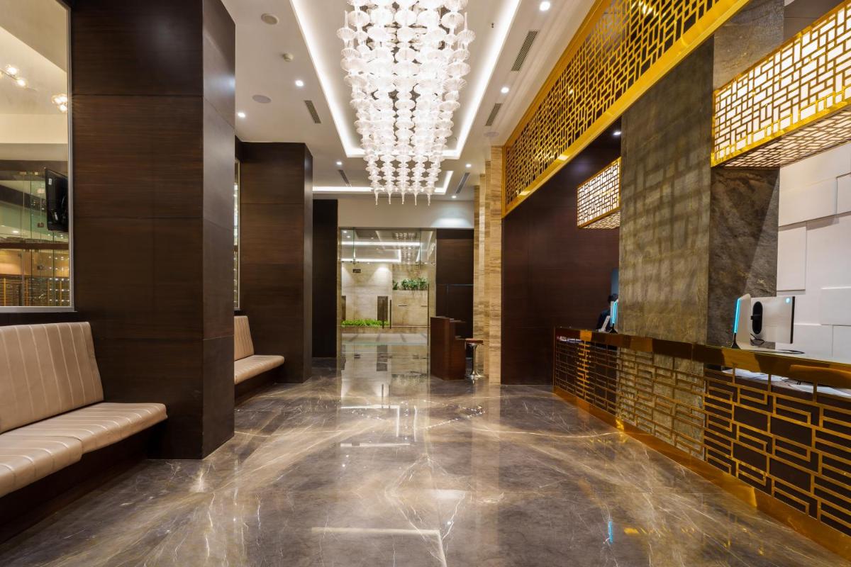 a lobby of a hotel with a chandelier at Pharos Hotels in Chennai