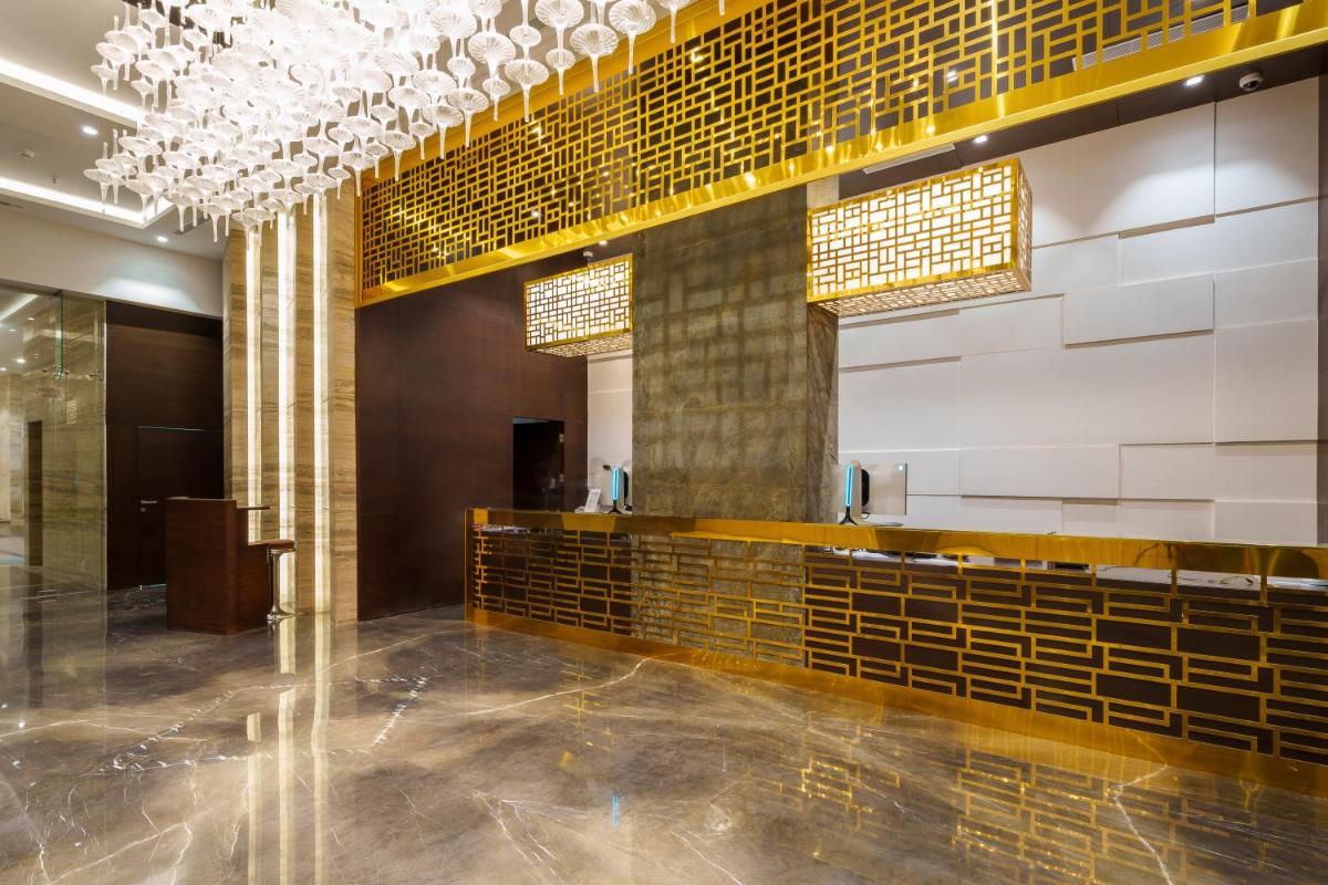 a lobby of a building with gold tiles and lights at Pharos Hotels in Chennai +30 photos
