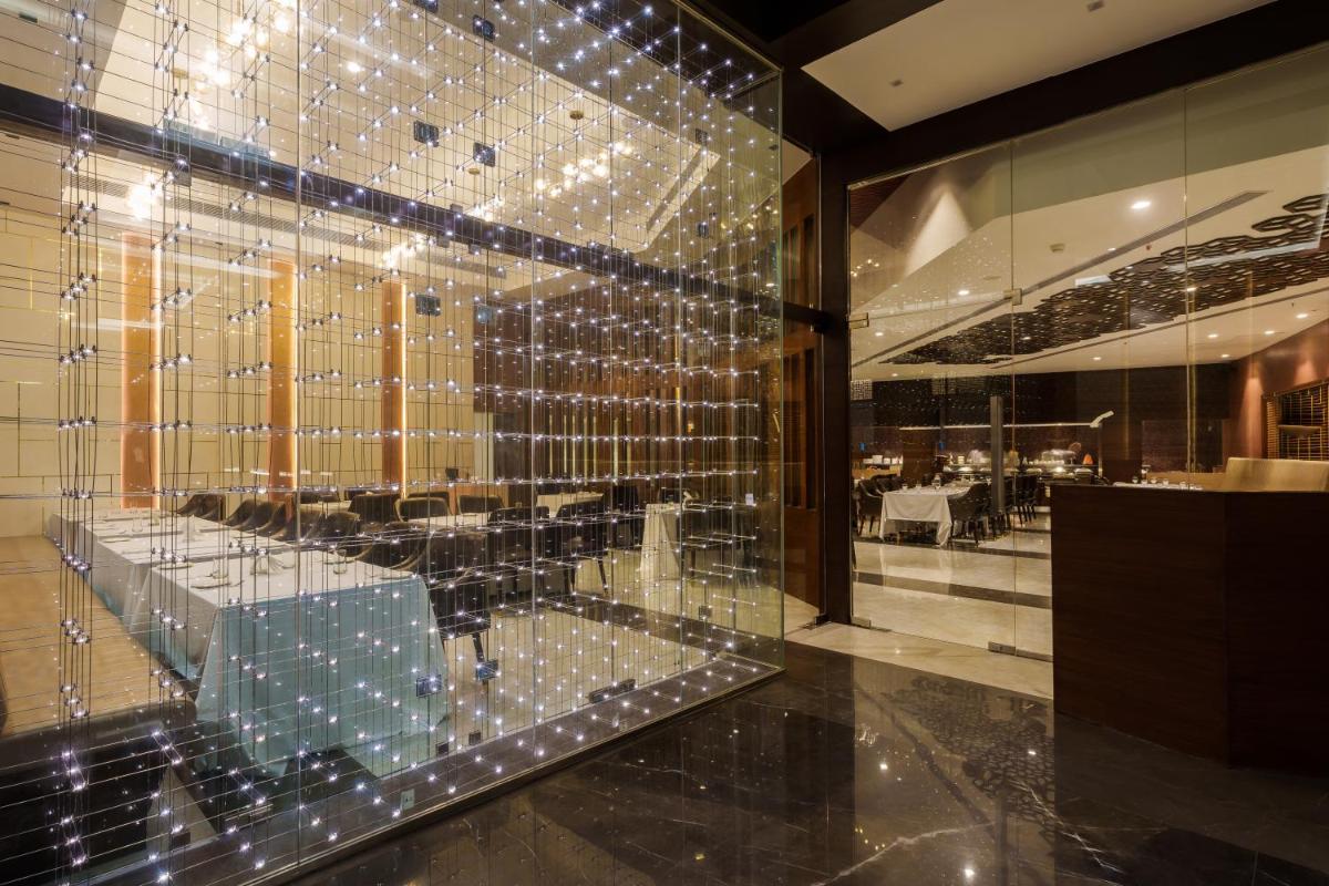 a room with a glass wall with a table in it at Pharos Hotels in Chennai