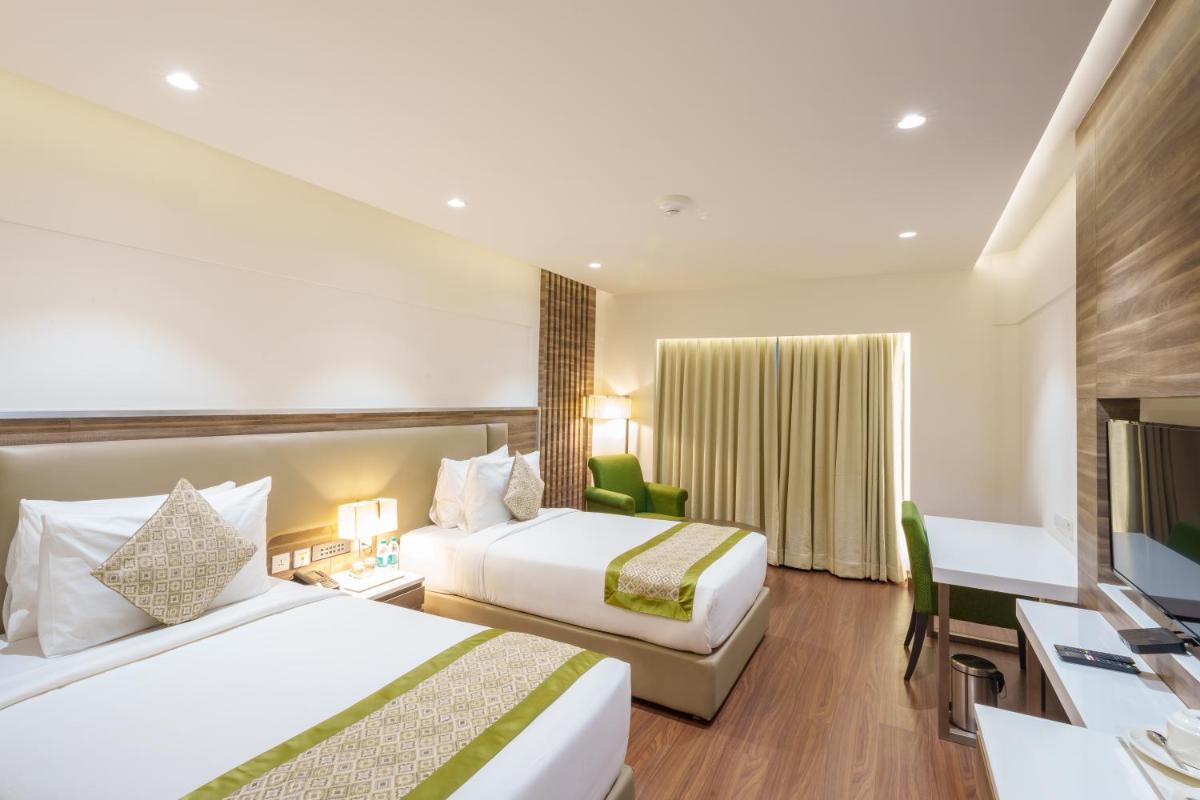 a hotel room with two beds and a desk at Pharos Hotels in Chennai