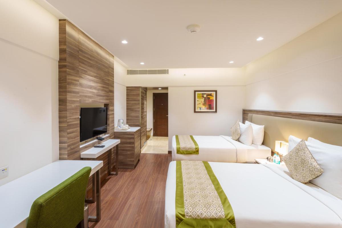 a hotel room with two beds and a flat screen tv at Pharos Hotels in Chennai