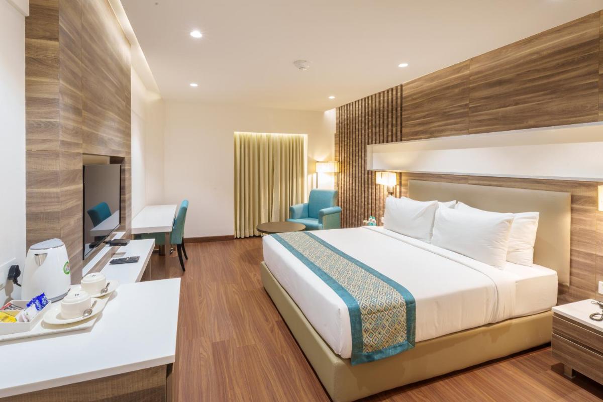 a hotel room with a bed and a desk at Pharos Hotels in Chennai
