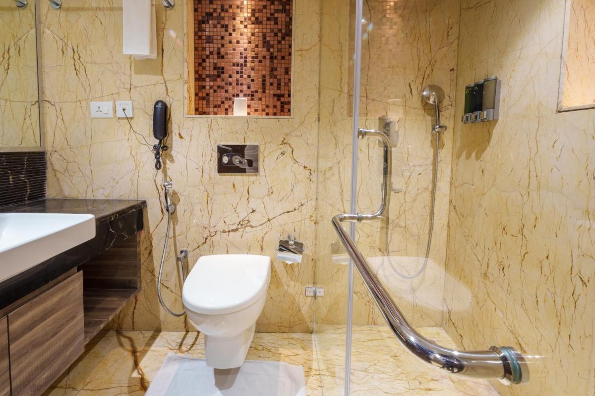 a bathroom with a shower and a toilet and a sink at Pharos Hotels in Chennai