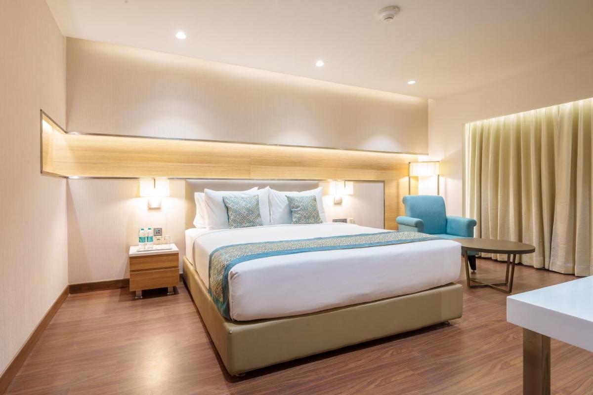 a hotel room with a bed and a desk at Pharos Hotels in Chennai
