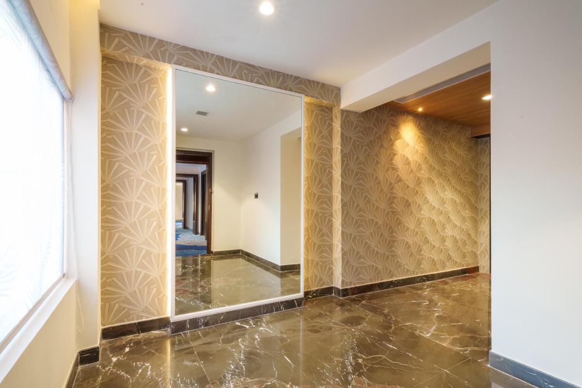 a hallway with a mirror and marble floor at Pharos Hotels in Chennai