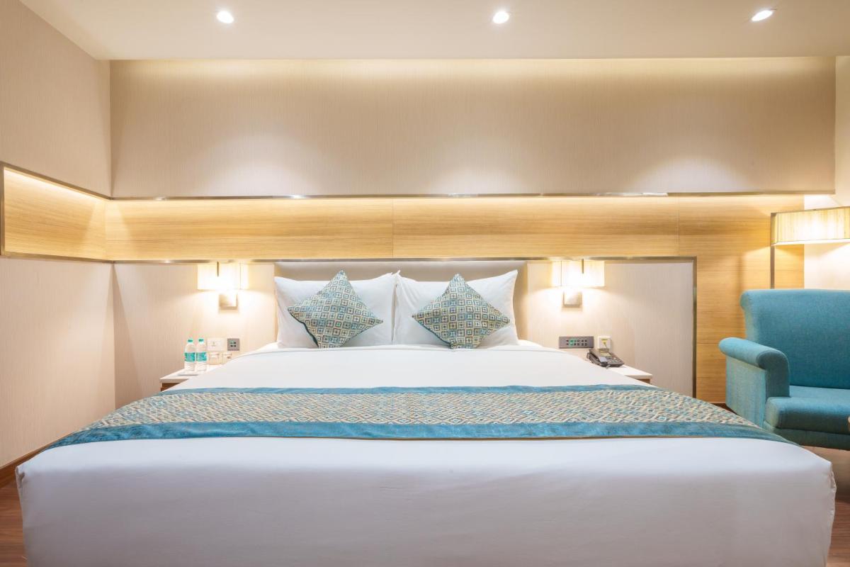 a bedroom with a large bed and a blue chair at Pharos Hotels in Chennai