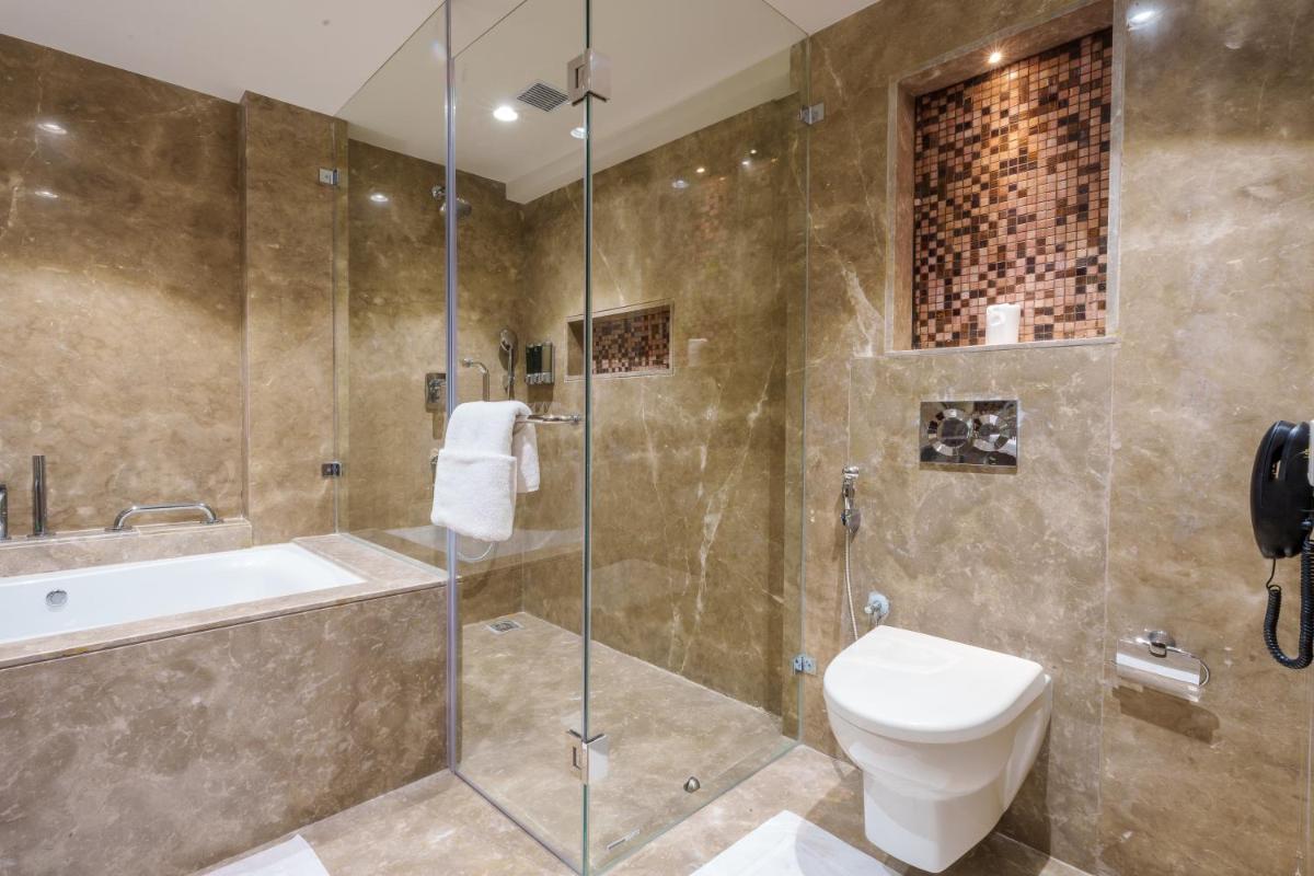 a bathroom with a shower and a toilet and a sink at Pharos Hotels in Chennai