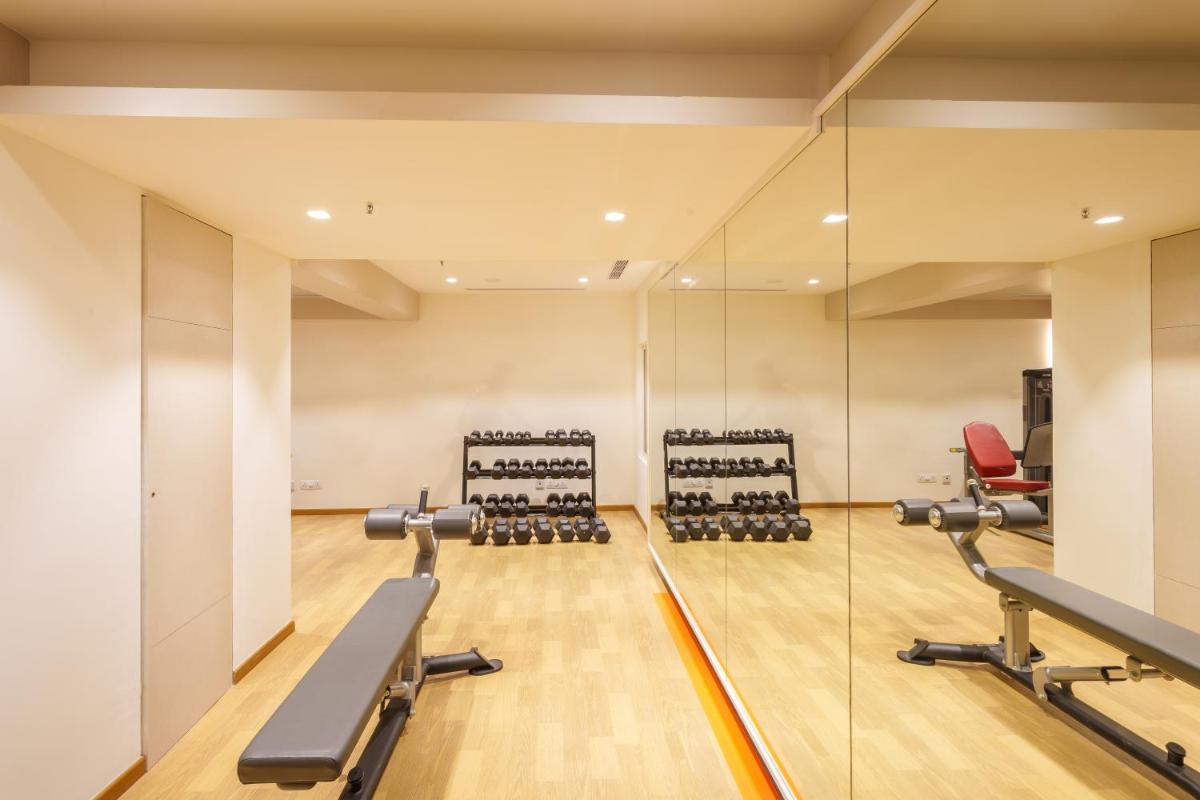 a gym with a mirror and cardio machines at Pharos Hotels in Chennai