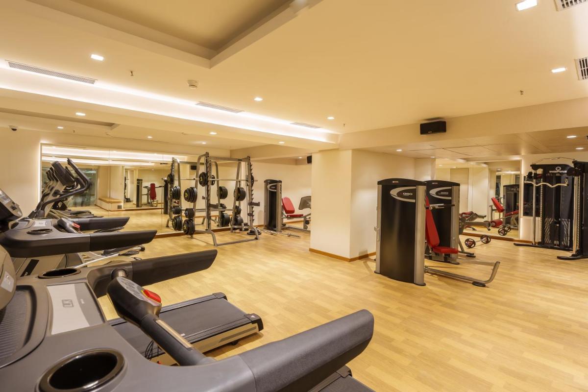 a gym with treadmills and machines in a room at Pharos Hotels in Chennai
