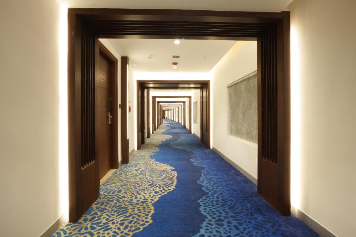 a hallway with a blue carpet with a long corridor at Pharos Hotels in Chennai