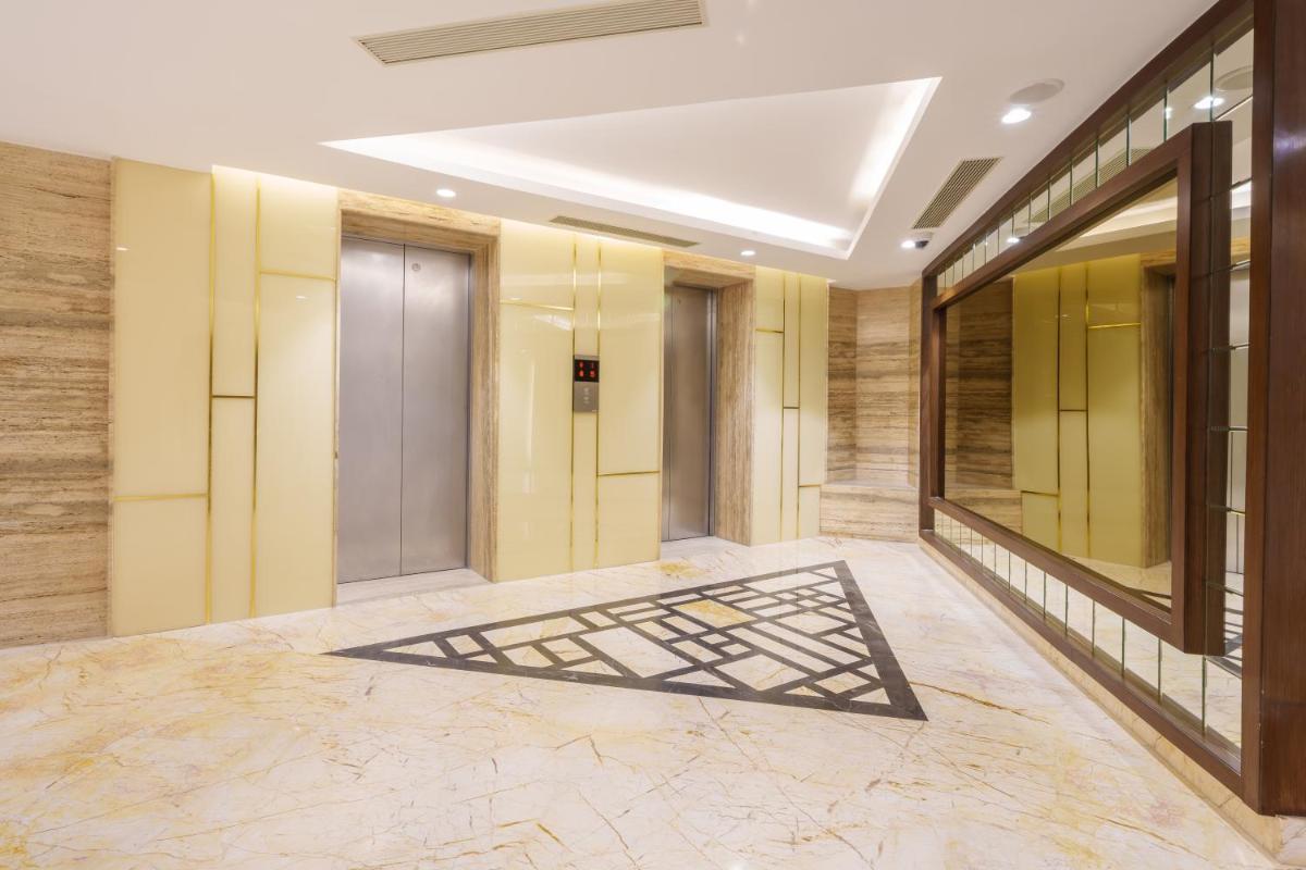 a hallway of a hotel with yellow walls and marble floors at Pharos Hotels in Chennai