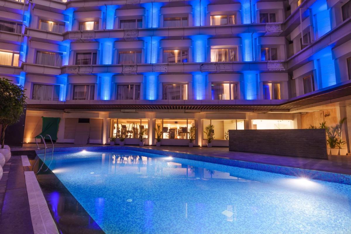 a swimming pool in front of a building with blue lights at Pharos Hotels in Chennai