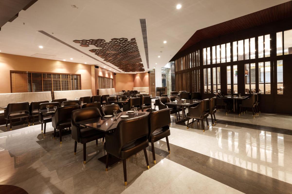 a restaurant with black tables and chairs and windows at Pharos Hotels in Chennai