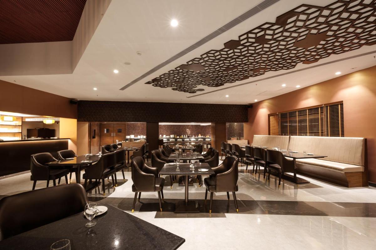 a restaurant with tables and chairs and a bar at Pharos Hotels in Chennai