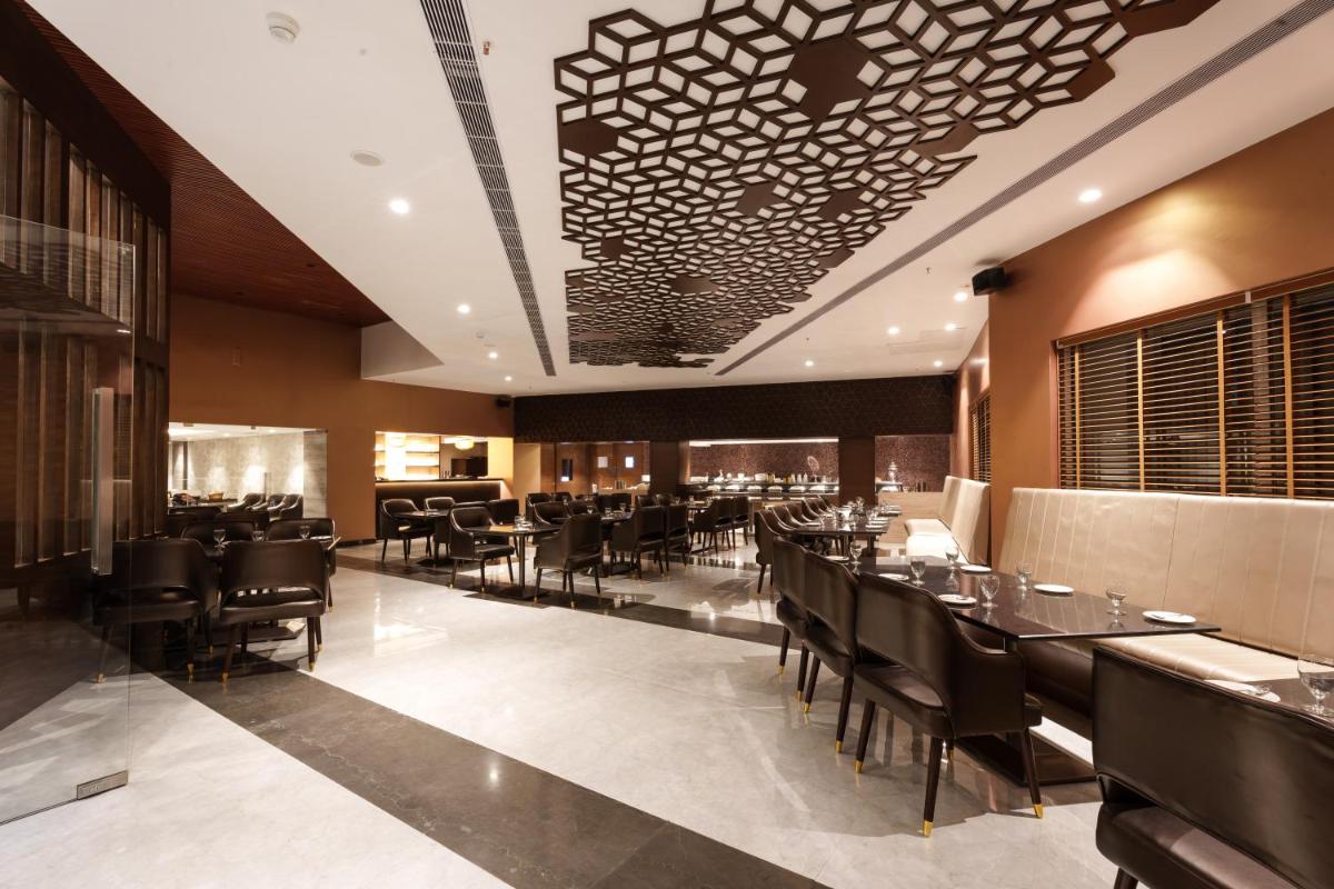 a dining room with tables and chairs and a ceiling at Pharos Hotels in Chennai