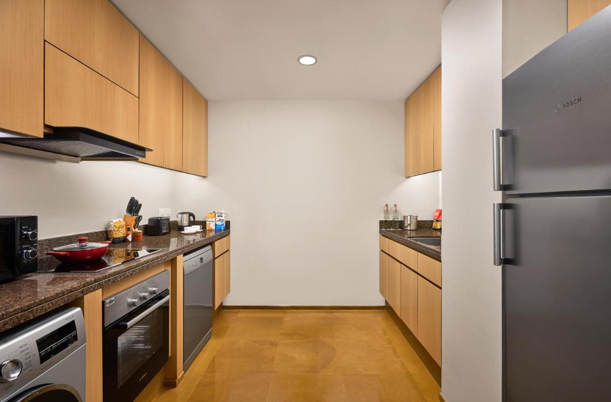 a kitchen with wooden cabinets and a stainless steel refrigerator at Grand Hyatt Mumbai Hotel and Residences in Mumbai