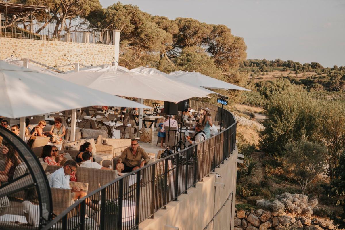 une foule de personnes assises à la terrasse d'un restaurant, munies de parapluies dans l'établissement Château Capitoul, à Narbonne
