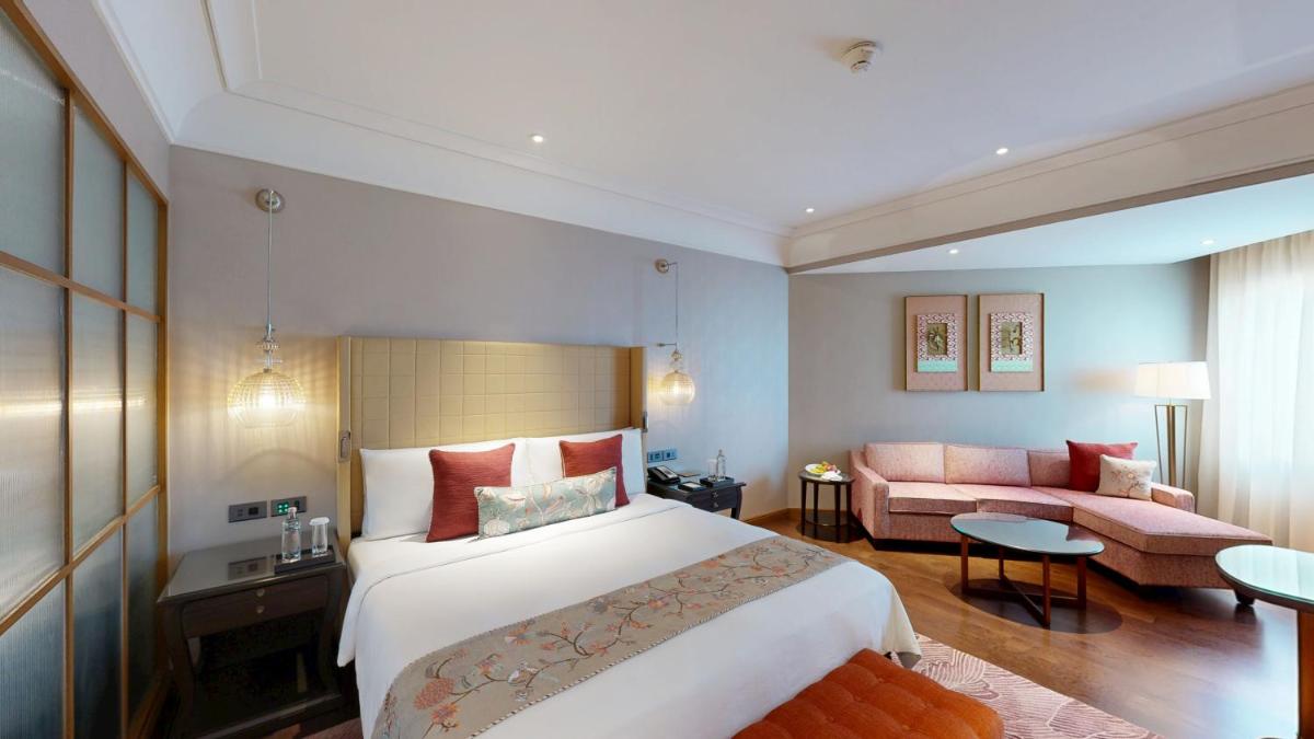 a hotel room with a large bed and a couch at The Leela Hyderabad Banjara Hills in Hyderabad