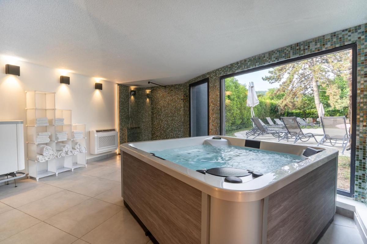 une grande baignoire dans une pièce avec une grande fenêtre dans l'établissement PoMo Hôtel & Restaurant, à Échirolles