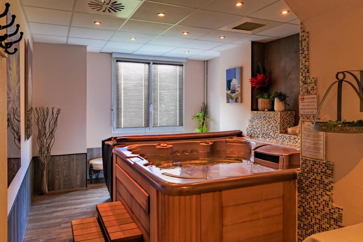 une grande baignoire dans une pièce avec un lavabo dans l'établissement Logis Central Hôtel - Restaurant & Spa, à Bort-les-Orgues