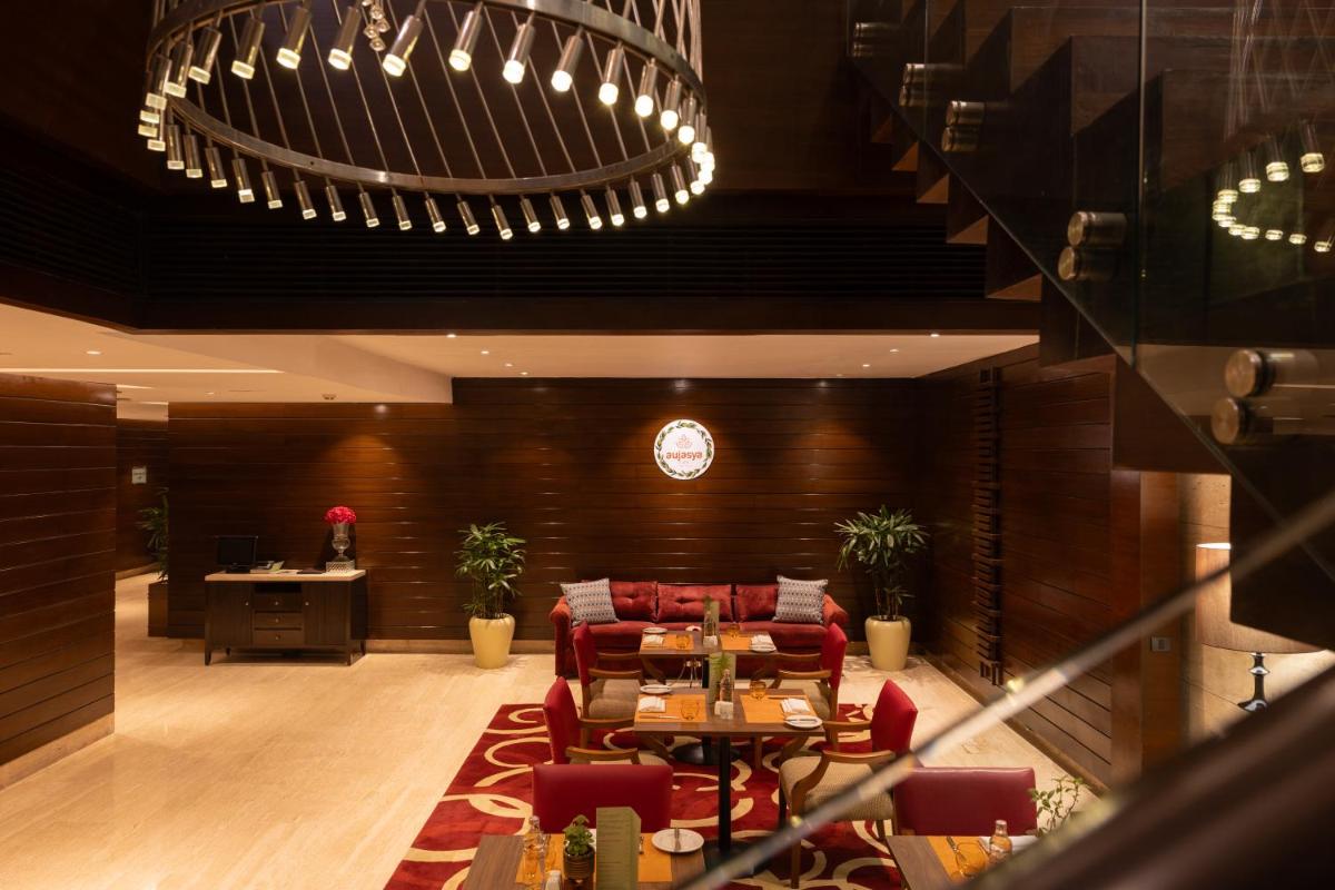 a lobby with red chairs and a table and a desk at The Leela Ambience Gurugram Hotel & Residences - The Luxury Urban Sanctuary in Gurgaon