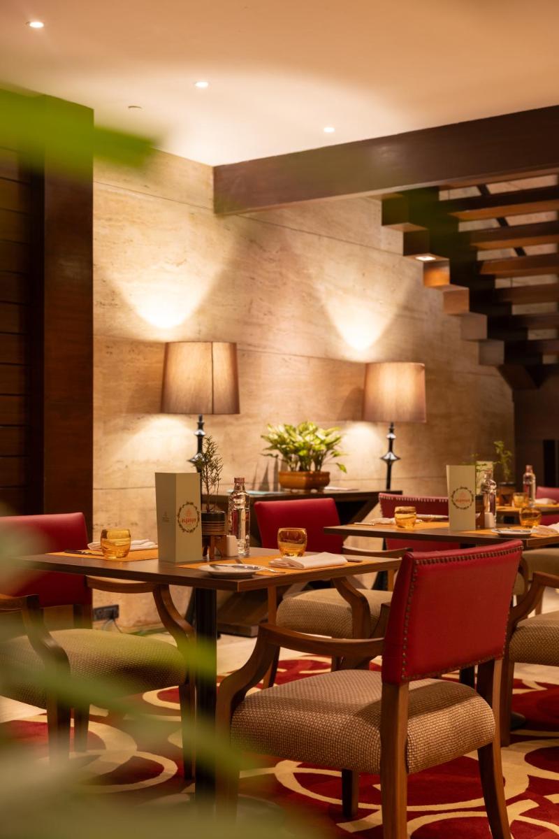 a restaurant with tables and chairs and a staircase at The Leela Ambience Gurugram Hotel & Residences - The Luxury Urban Sanctuary in Gurgaon