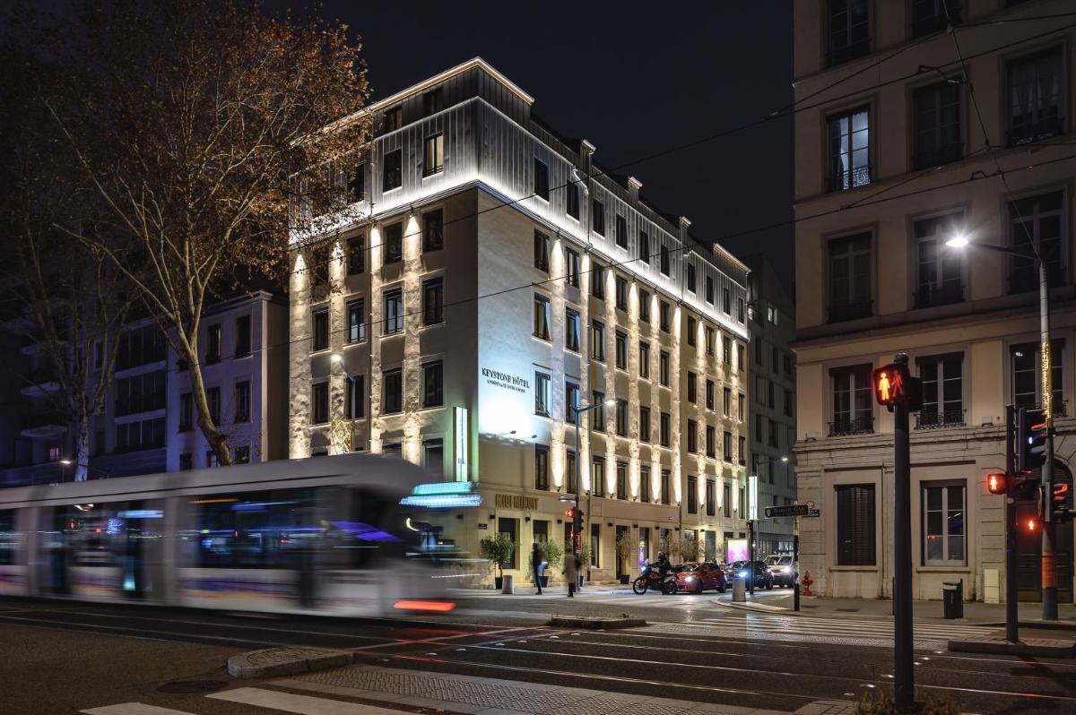 un bâtiment situé dans une rue de la ville la nuit avec un bus dans l'établissement Keystone Hôtel & Spa, à Lyon