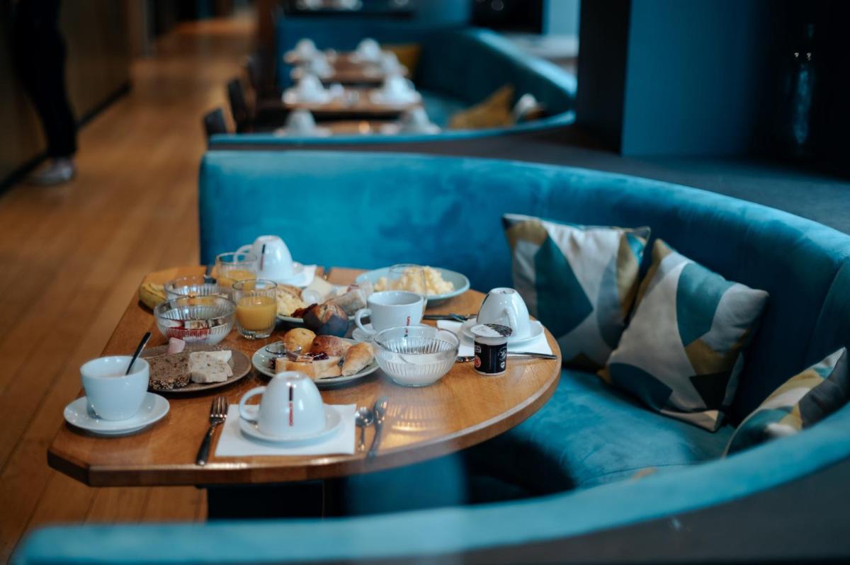 une table avec des assiettes de nourriture sur un canapé bleu dans l'établissement Keystone Hôtel & Spa, à Lyon