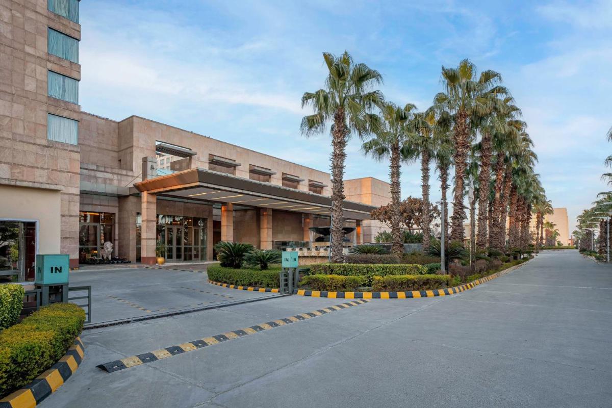 a building with palm trees in front of it at Radisson Blu Hotel Amritsar in Amritsar