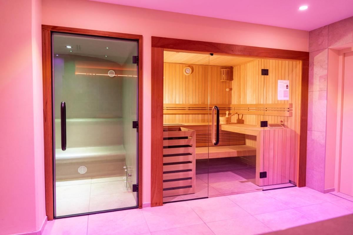 Cette chambre rose dispose d'une porte en verre menant à une salle de bains. dans l'établissement Eco-Domaine La Fontaine - RESIDENCE-SPA - Plage de la Fontaine aux Bretons, à Pornic
