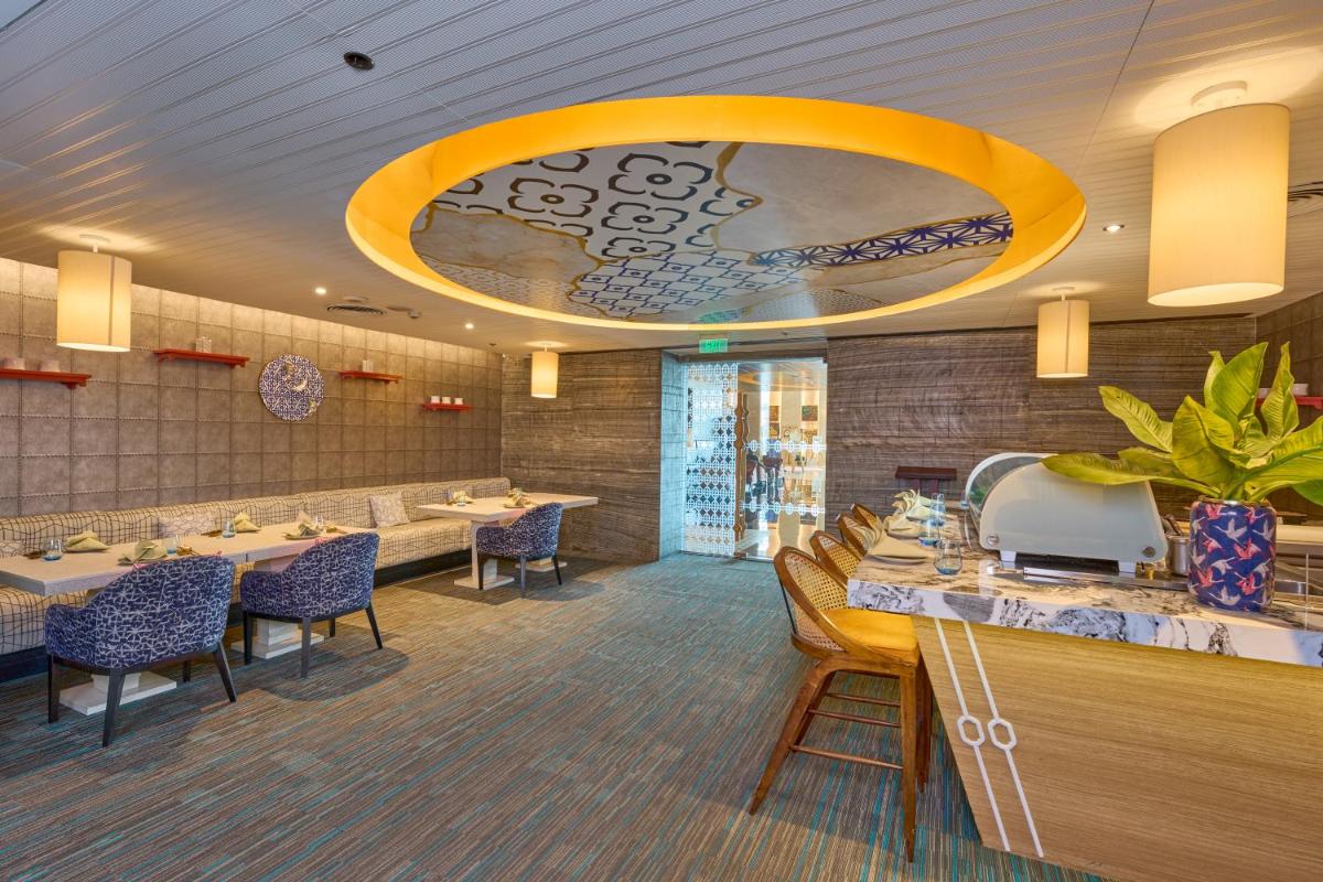 a restaurant with tables and chairs and a large chandelier at Crowne Plaza Kochi by IHG in Cochin