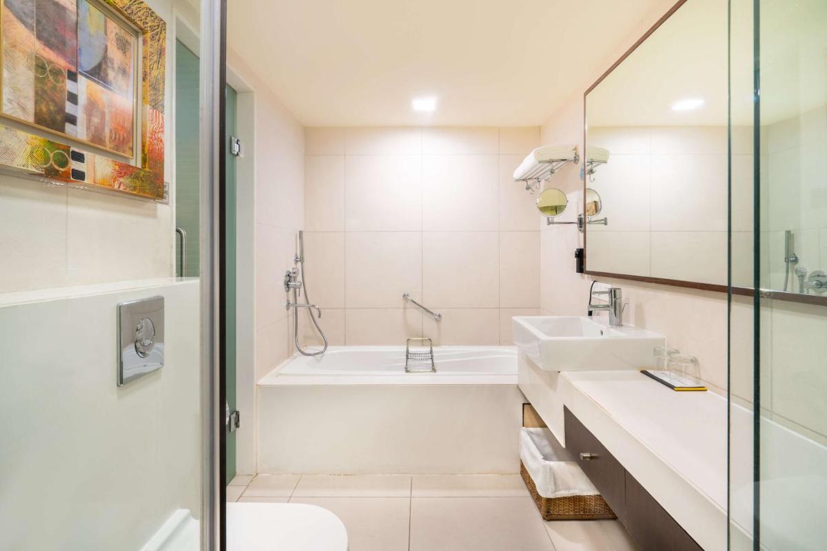 a bathroom with a sink and a tub and a toilet at Radisson Gurugram Sohna Road City Center in Gurgaon a bathroom with a sink and a tub and a toilet at Radisson Gurugram Sohna Road City Center in Gurgaon