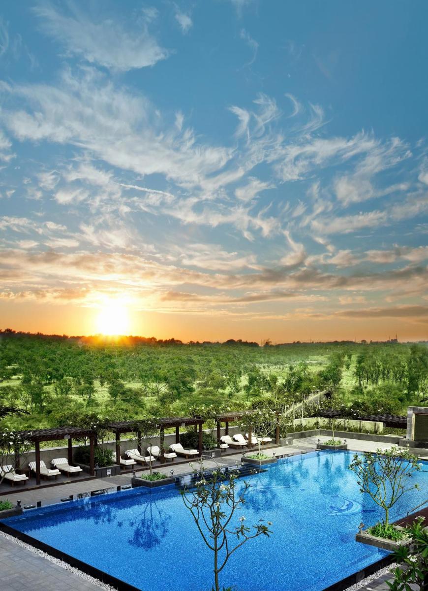 a view of a pool at a resort at sunset at The Leela Ambience Gurugram Hotel & Residences - The Luxury Urban Sanctuary in Gurgaon
