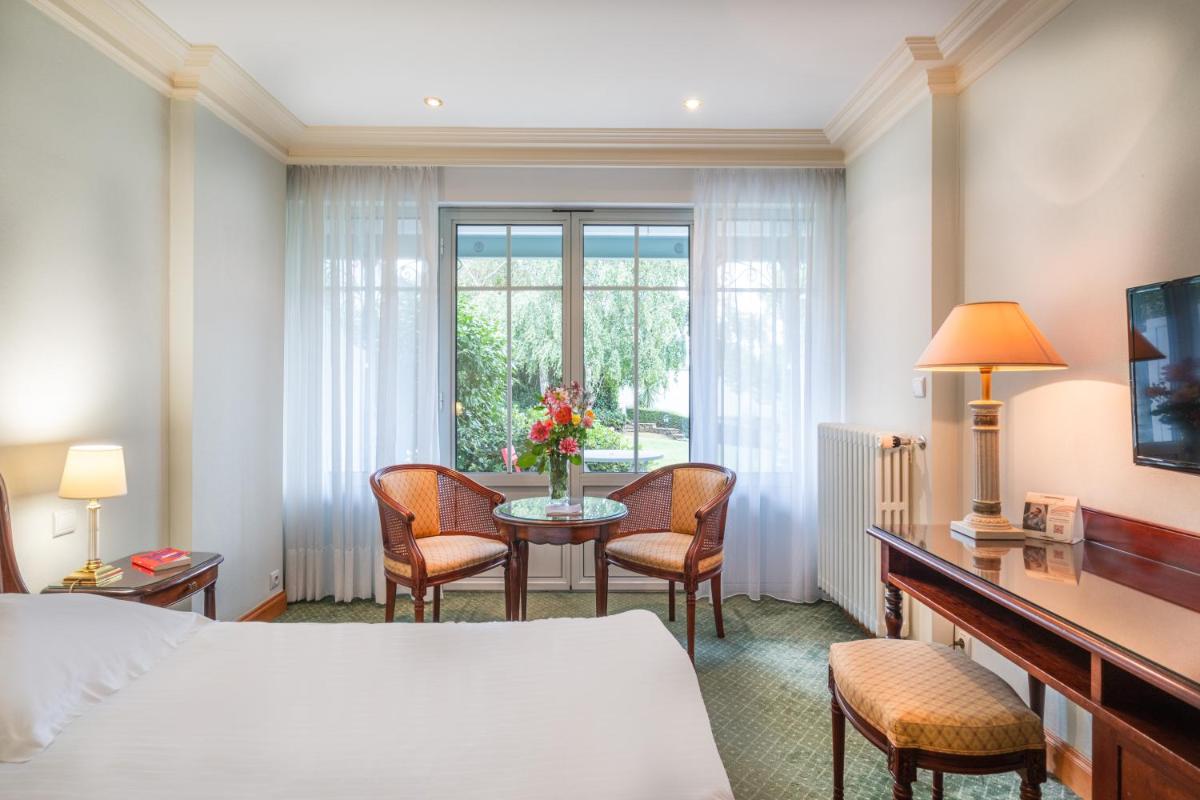 une chambre d'hôtel avec un lit et une table avec des chaises dans l'établissement Domaine du Limonay, The Originals Collection, à Saint-Méloir-des-Ondes