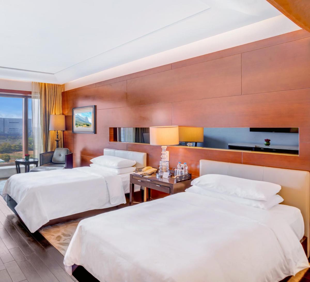 a hotel room with two beds and a table at The Leela Ambience Gurugram Hotel & Residences - The Luxury Urban Sanctuary in Gurgaon