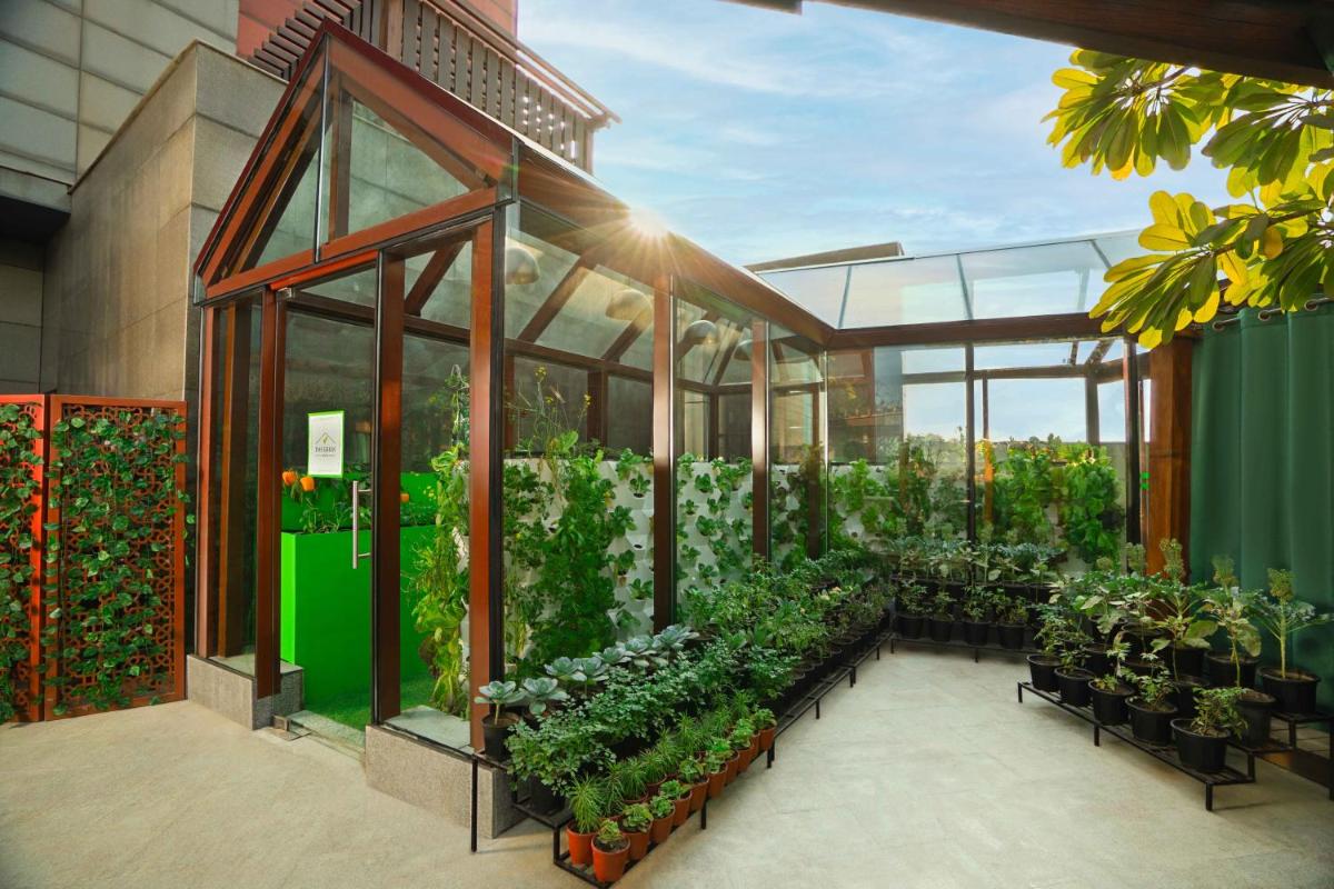 a greenhouse filled with plants in a building at The Leela Ambience Gurugram Hotel & Residences - The Luxury Urban Sanctuary in Gurgaon